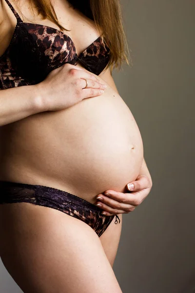 Zwangere vrouw dragen van ondergoed haar buik aan te raken Stockfoto