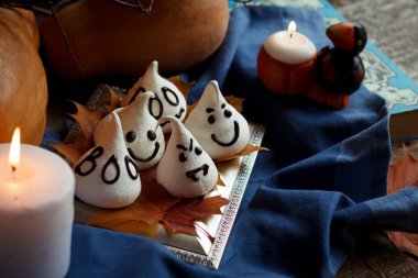 Komik beze hayaletler sonbahar süslemeleri Cadılar Bayramı partisi için. Altın yaprakları, kabak, mavi textil ve mum ışığında. Cadılar Bayramı kavramı