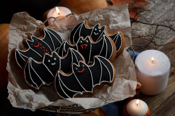 Murciélagos de Halloween galletas de azúcar con decoraciones, velas de luz y fondo viejo de madera —  Fotos de Stock