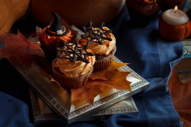 Cadılar Bayramı Cucpcakes metin topper dekorasyon ve portakal krema ile. Mumlar ve kabak arka plan
