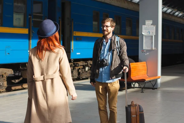 Woman meeting her boyfriend from his trip at the train station. Tourist Man with luggage and photo camers. Travel concept. Redhair girlfriend. — Stock Photo, Image