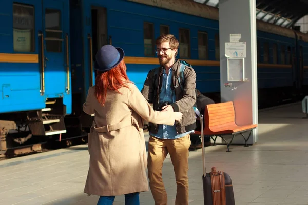 Woman meeting her boyfriend from his trip at the train station. Tourist Man with luggage and photo camers. Travel concept. Redhair girlfriend. — Stock Photo, Image