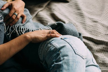 Kucaklayan ve evde yatakta rahatlatıcı youngcouple görünümünü kırpılmış. Vintage rahat bir görünüm. Yırtık kot. Kış saati