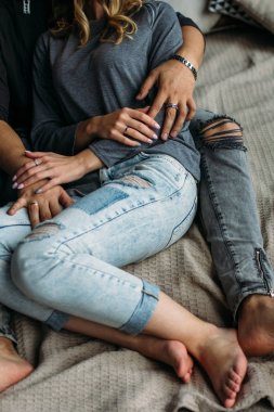Kucaklayan ve evde yatakta rahatlatıcı youngcouple görünümünü kırpılmış. Vintage rahat bir görünüm. Yırtık kot. Kış saati