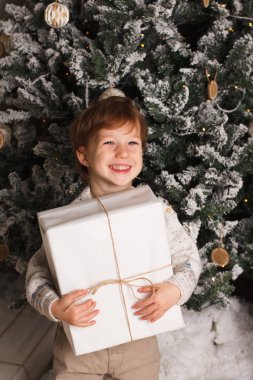 Noel Noel ağacının etrafında bir genç çocuk rahat atmosfer portresi. Şirin bebek beyaz hediye kutusu tutarak. Dikey fotoğraf, kopya cpace
