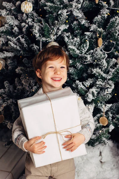 Noel Noel ağacının etrafında bir genç çocuk rahat atmosfer portresi. Şirin bebek beyaz hediye kutusu tutarak. Dikey fotoğraf, kopya cpace