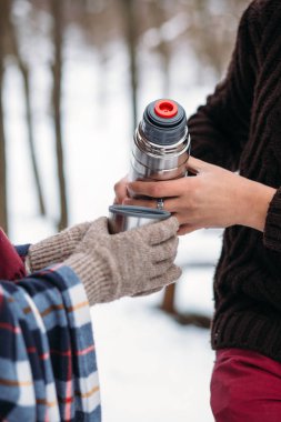 Bir fincan çay bir termos ormanda kış piknik üzerinde. Bir sıcak eldiven eller kadın