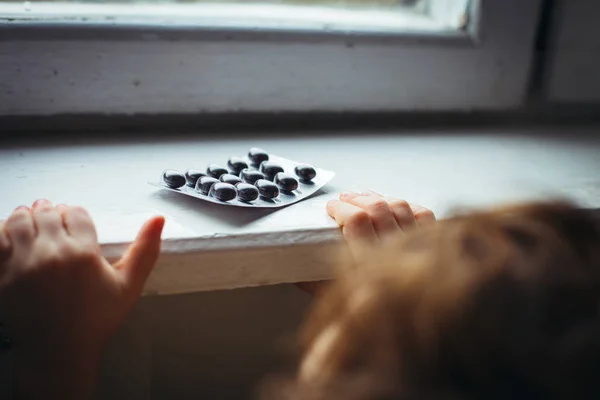 El niño toma un paquete de pastillas. Una situación peligrosa. Un niño pequeño curioso acerca de un envase de medicamentos recetados que ilustra la importancia de la seguridad de los medicamentos y la supervisión y comunicación de los padres . —  Fotos de Stock