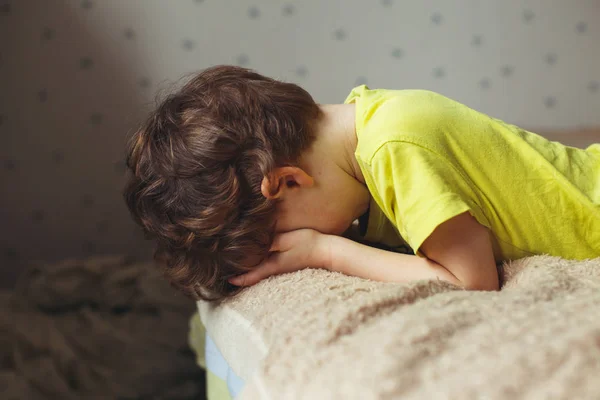 Niño cansado acostado en la cama con la cara baja. Niñito llorón —  Fotos de Stock