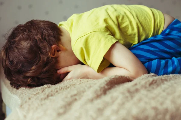 Stanco ragazzo bambino sdraiato sul letto con la faccia a terra. Piangere bambino — Foto Stock
