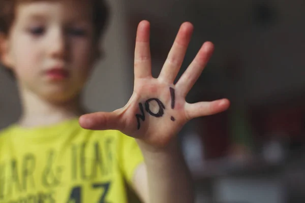 Garçon de 3 ans faisant un signal d'arrêt avec sa main. Mot Pas d'écriture sur la paume. Concept de sécurité et de violence — Photo