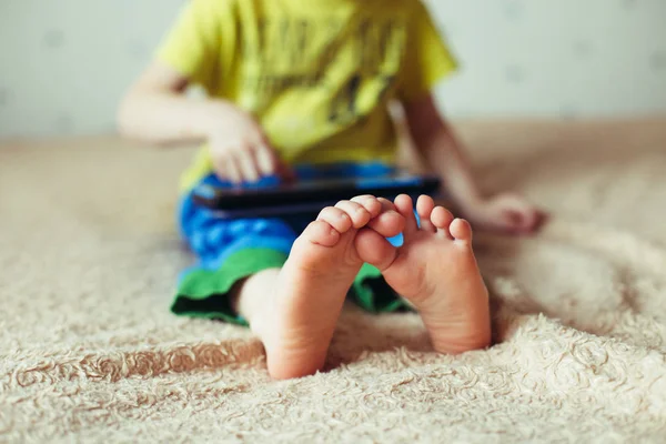 Niño pequeño usando la tableta en una cama — Foto de Stock