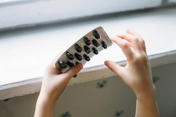 Bebé en peligro jugando con un paquete de pastillas en casa sin padres. Concepto de seguridad —  Fotos de Stock