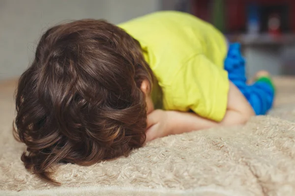 Niño cansado acostado en la cama con la cara baja. Niñito llorón —  Fotos de Stock