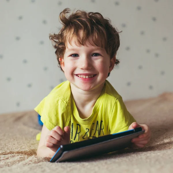 Jongetje glimlachend en kijken op tablet, met behulp van moderne technologie. Vierkante foto — Stockfoto