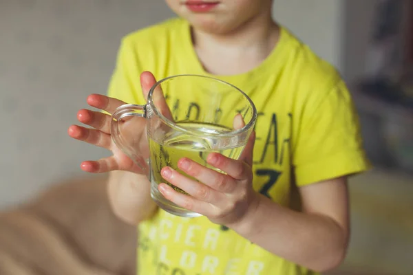 Мальчик, мальчик начинает свое утро со стакана пресной воды. Маленький кудрявый мальчик пьет воду. Концепция воды — стоковое фото