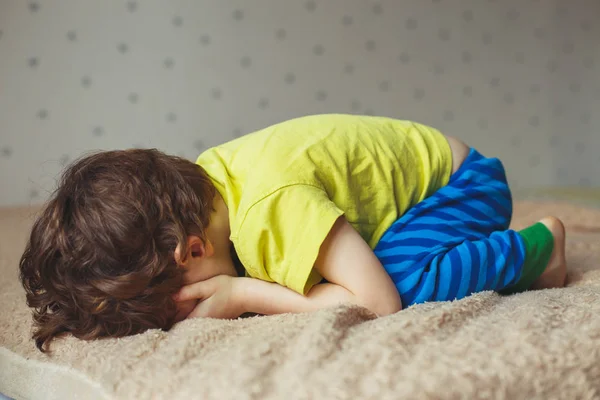 Niño cansado acostado en la cama con la cara baja. Niñito llorón —  Fotos de Stock