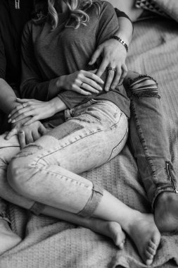 Kucaklayan ve evde yatakta rahatlatıcı youngcouple görünümünü kırpılmış. Vintage rahat bir görünüm. Yırtık kot. Kış saati