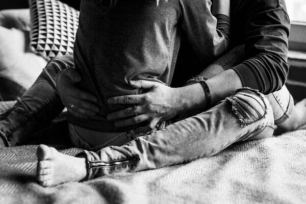 Young beautiful pair of lovers hug and kiss. Cropped image. Legs in grey ragged jeans