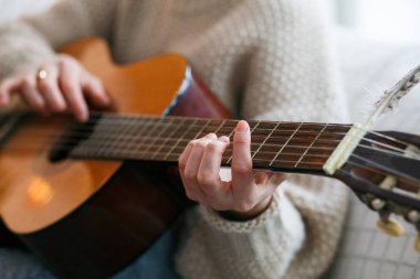 Gitar el sanatçı tarafından ya da müzisyen oynamak. Örme kazak eller genç kadın. Ev müzik parti