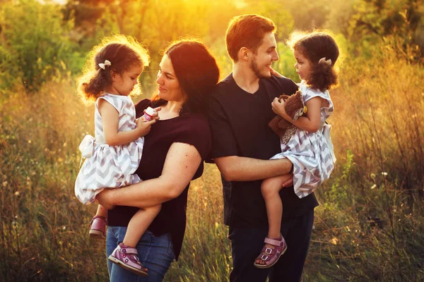 Familia joven y feliz con dos hijos al aire libre. Gemelas niñas — Foto de Stock