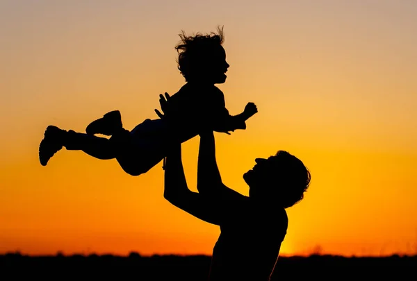 Gelukkig Papa gooit de peuter bij zonsondergang. Gelukkige familie concept. Glimlachend jongetje. — Stockfoto