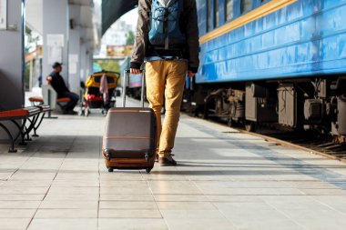 Seyahat kavramı. Erkek spor ayakkabı ayakkabı giymek ve tren istasyonunda Bagaj ile seyahat.