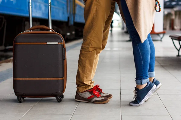 Legs Loving Couple happy hugging in the train station of a country after arrival with a warm sunlight background. Trolley broun bag. Travel concept — Stock Photo, Image