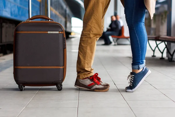 Legs Loving Couple happy hugging in the train station of a country after arrival with a warm sunlight background. Trolley broun bag. Travel concept — Stock Photo, Image