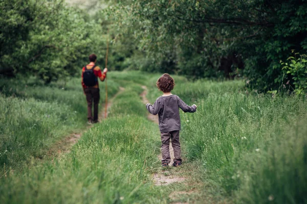 Father and son walking in spring forest. Back view. Green grass background — Stock Photo, Image