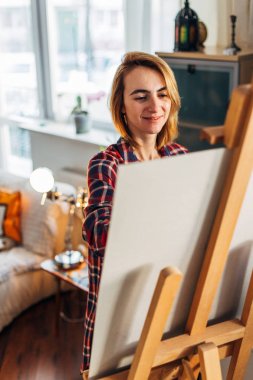 Sanat, yaratıcılık, hobi, iş ve yaratıcı işgal kavramı. Arkadan Görünüş parmakla boyama şövale önünde kalmak meşgul kadın sanatçı