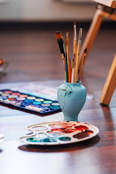 Artist paint brushes and palette on wooden background