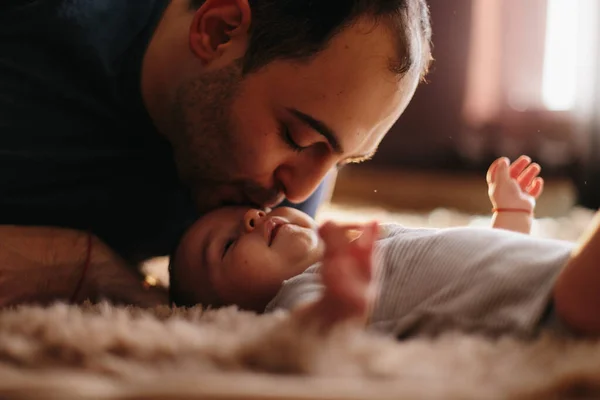 Atractivo padre joven que se inclina a besar a su bebé. Los padres amor concepto — Foto de Stock