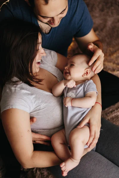 彼の両親がベッドで遊んでいる赤ん坊。家庭で幸せな家族。ライフスタイルの居心地の良い写真。小さな男の子4ヶ月 — ストック写真