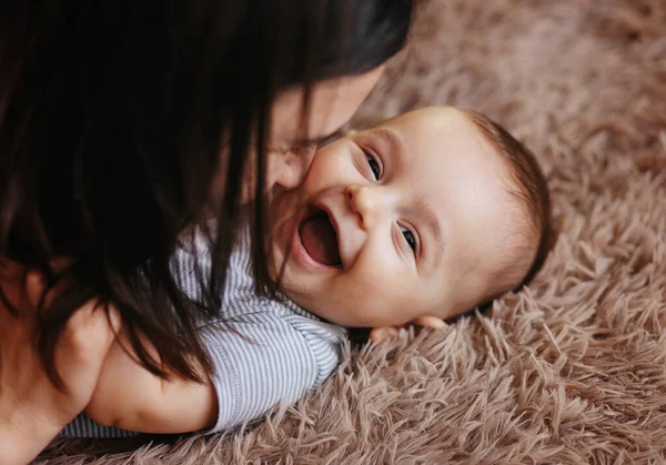 Happy cheerful family. Mother and baby kissing, laughing and hugging. Home happiness — Stock Photo, Image
