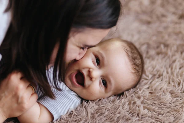 Gelukkige vrolijke familie. Moeder en baby zoenen, lachen en knuffelen. Thuis geluk — Stockfoto