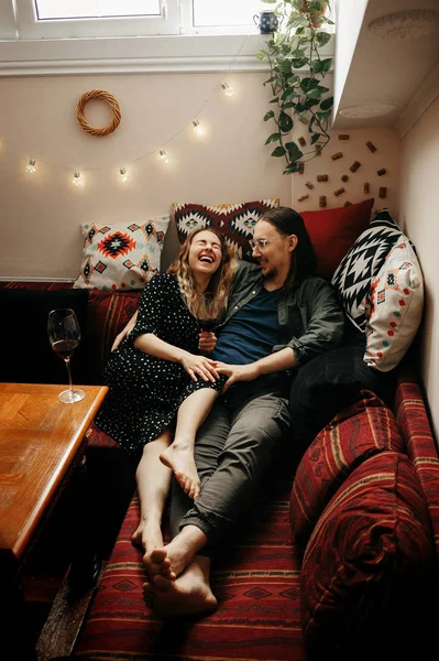 Romantic couple having dinner at home. Man pouring wine. Beautiful cozy interior