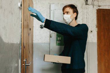 Kurye, koruyucu maskeli kurye Coronavirus salgını sırasında, COVID-19, kahverengi kutuda güvenli bir şekilde online alışverişi teslim ediyor. Evde kal, güvenli konsept.