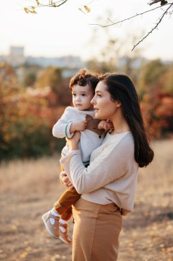Mutlu bir aile. Uzun saçlı güzel bir anne ve oğlu parkta eğleniyor. Olumlu insan duyguları