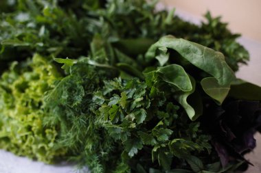 Masadaki yeşil yapraklı sebzelerden oluşan bahar vitamini seti..