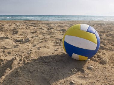 Kumsalda mavi, beyaz ve sarı voleybol topu