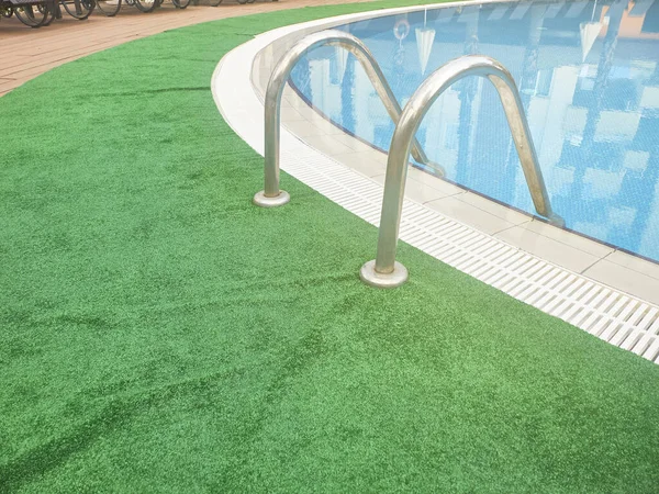 Handräcke stege av pool och grön matta — Stockfoto