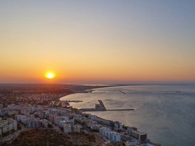 Güneş sahil kasabasının üzerinden doğuyor. Şehrin, denizin ve limanın havadan görünüşü