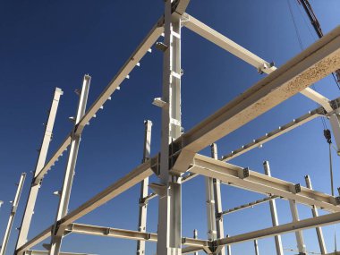 Prefabrik endüstriyel binanın metal iskeleti. Sütunlar ve kirişler açık mavi gökyüzünün karşısında