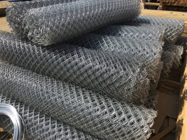 Metal ağ örgüsü rulo ve çelik tel bobinlere sarılmış. Yuvarlak zincirli tel örgü