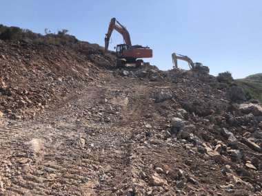 Hidroçekiç, yol inşaatı sırasında kayalık topraklarda taş kırıyor.