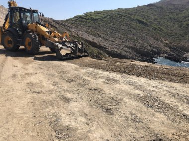 Sarı yük kepçesi yol inşaatı sırasında bir yol yüzeyi yapmayı planlıyor. Toprak taşıma, kazı, kazı