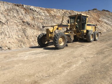 Yol yüzeyinin planlanması. Yol inşaatı sırasında motor greyderi. Toprak taşıma, kazı, kazı