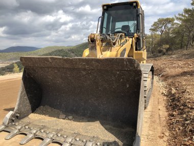 Bir kova böcek buldozer. Yol inşaatında yer değiştiren ağır makineler