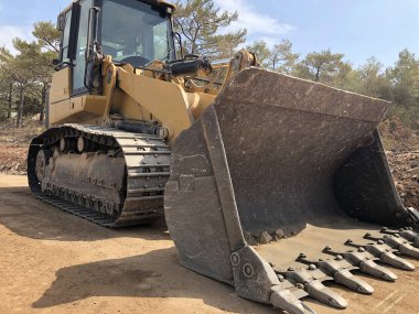 Bir kova böcek buldozer. Yol inşaatında yer değiştiren ağır makineler
